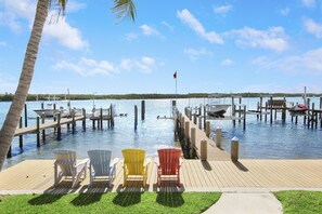 A dock with chairs and a flag, a clear sky, and calm water.