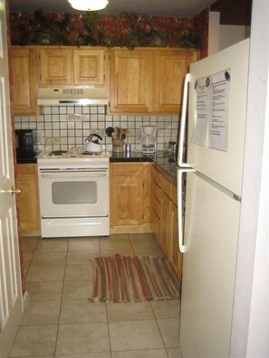 Kitchen area with stove, coffee maker, and refrigerator.