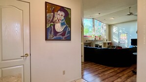 Un salon avec un canapé d’angle noir, un tableau accroché au mur et un plancher en bois.