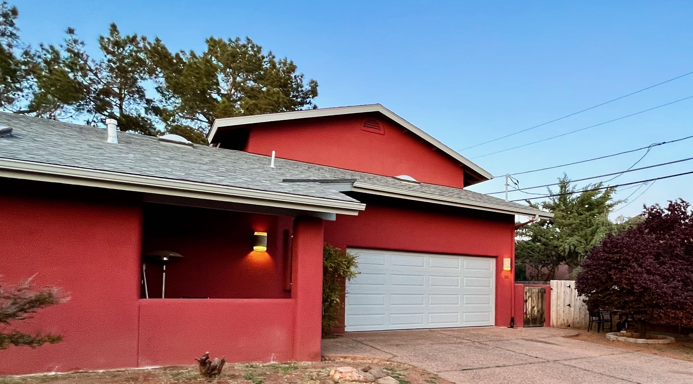 Ein rotes Haus mit Garage, einer kleinen Veranda und einem Baum im Vorgarten.