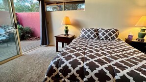 Une chambre à coucher avec un lit, deux lampes de chevet, une fenêtre et une vue sur l’extérieur.