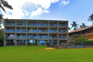 A multi-story hotel with balconies, a swimming pool, and a well-maintained lawn. - Leinaala Oceanfront 405 Panoramic Ocean View, Great Rates, Steps to the beach (Kihei)