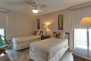 A hotel room with two beds, a ceiling fan, a nightstand with a lamp, and artwork on the walls. - Leinaala Oceanfront 405 Panoramic Ocean View, Great Rates, Steps to the beach (Kihei)