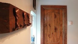 A wooden door with a rustic finish, a wall-mounted coat rack with multiple hooks, and a small figurine. - Tiny home in the Big Sky  (Somers)