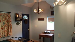 A room with a blue door, a small table with a radio, a fish decoration, and a chandelier. - Tiny home in the Big Sky  (Somers)