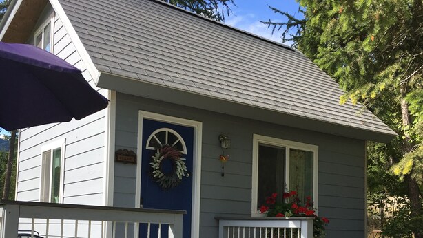 A small house with a blue door, a welcome wreath, and a porch with steps. - Tiny home in the Big Sky  (Somers)