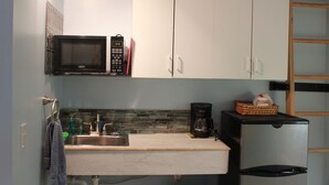 A compact kitchen with a microwave, coffee maker, and a small refrigerator. - Tiny home in the Big Sky  (Somers)