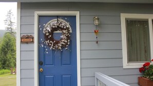 A blue door with a wreath, a welcome sign, and a lantern on the wall. - Tiny home in the Big Sky  (Somers)