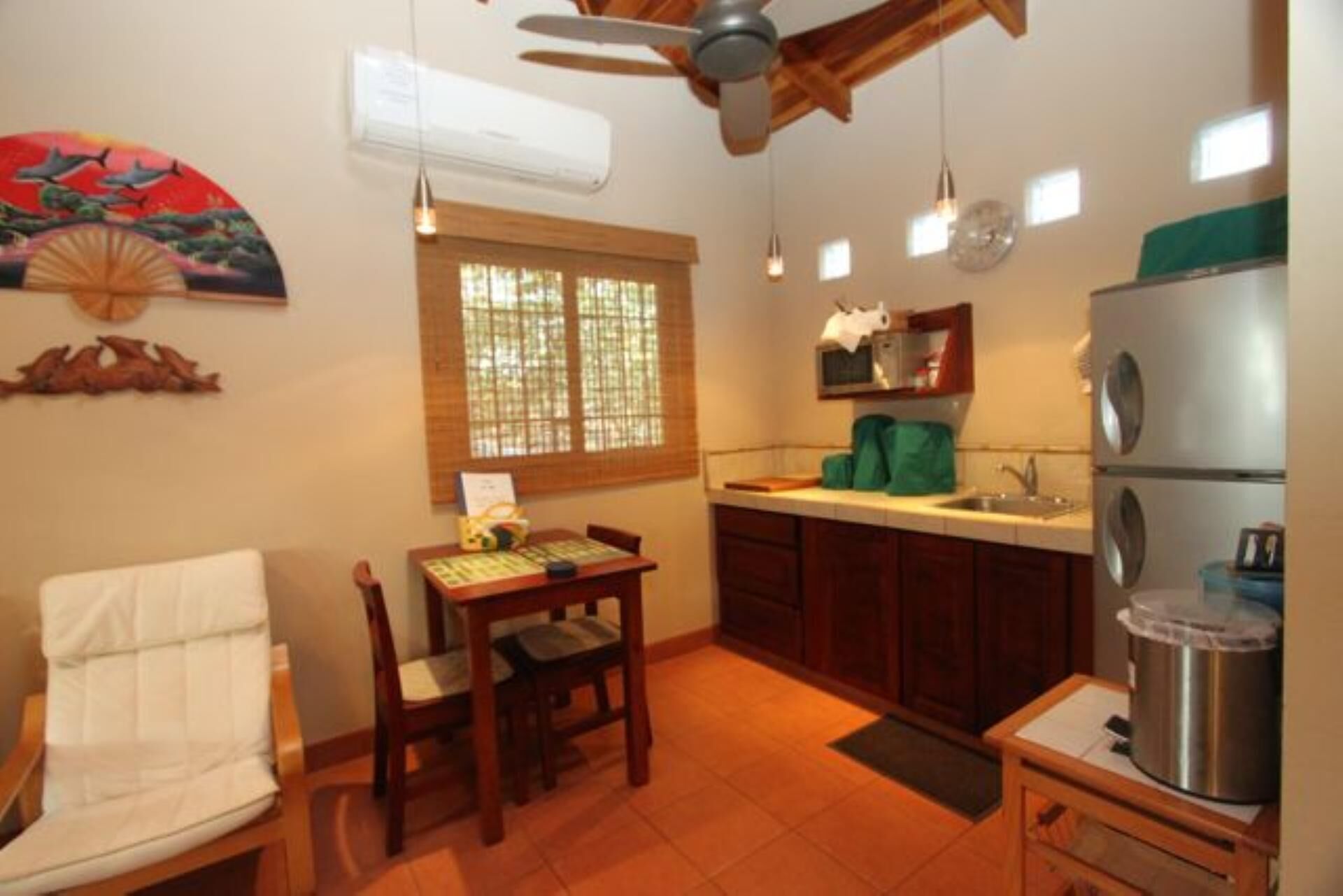 Une cuisine compacte comprenant un coin repas, un ventilateur de plafond, une fenêtre avec stores et un réfrigérateur.
