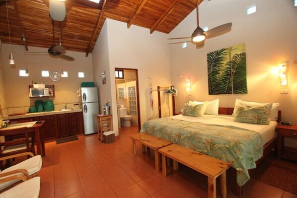 A cozy room with a bed, a desk, and a kitchenette.