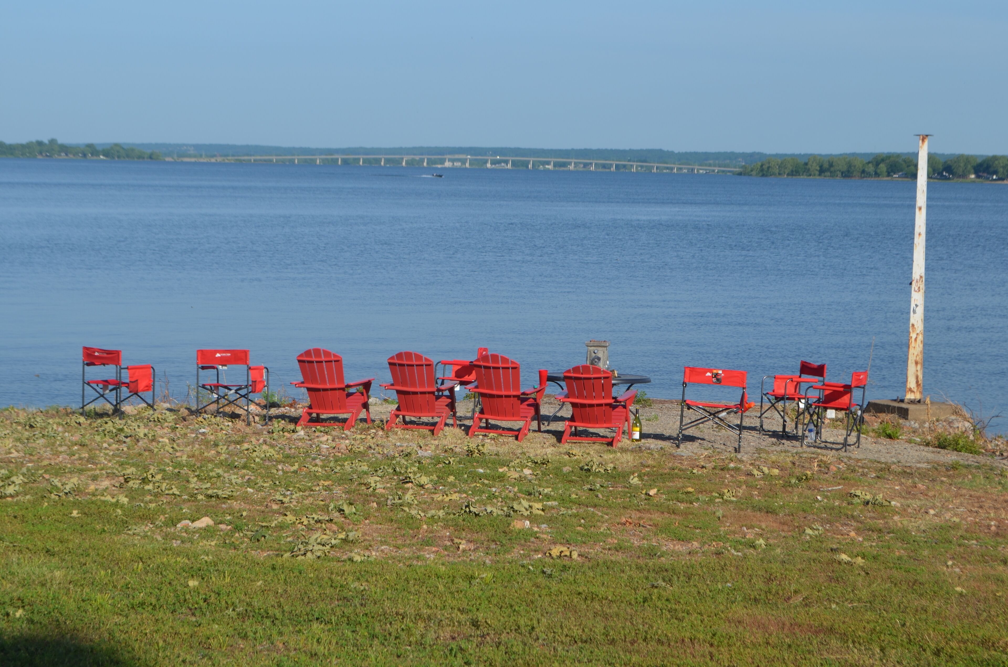 Une vue sur le lac, avec des chaises Adirondack rouges et un pont en arrière-plan.