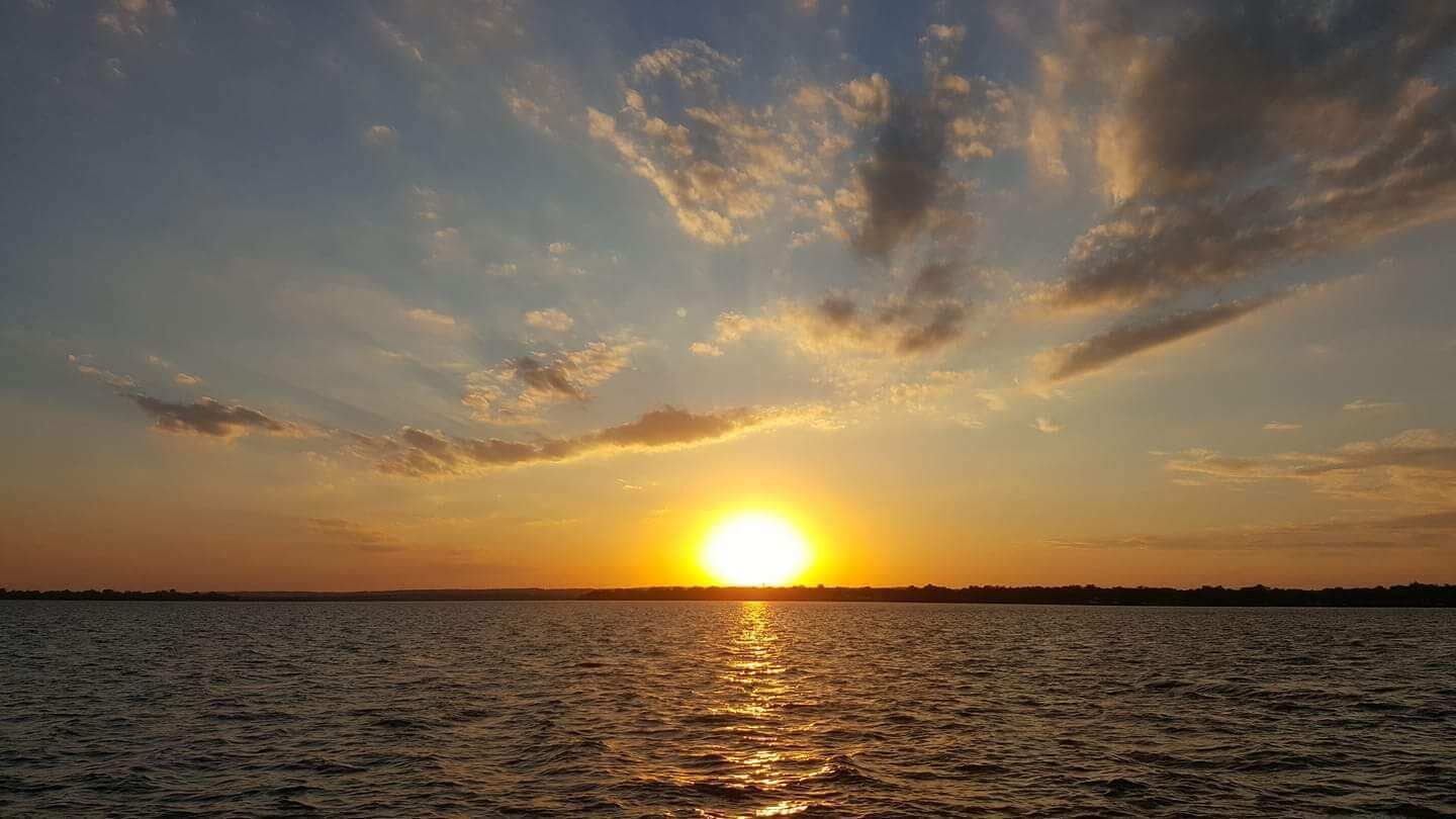 A sunset over a body of water with a clear horizon.