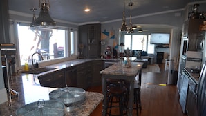 A spacious kitchen with granite countertops, a central island with stools, and a large window providing natural light. - GRAND PANORAMIC RETREAT, 6 BR, 3 BA, 300' Lakefront, Dock & Launch! NEW (Grove)