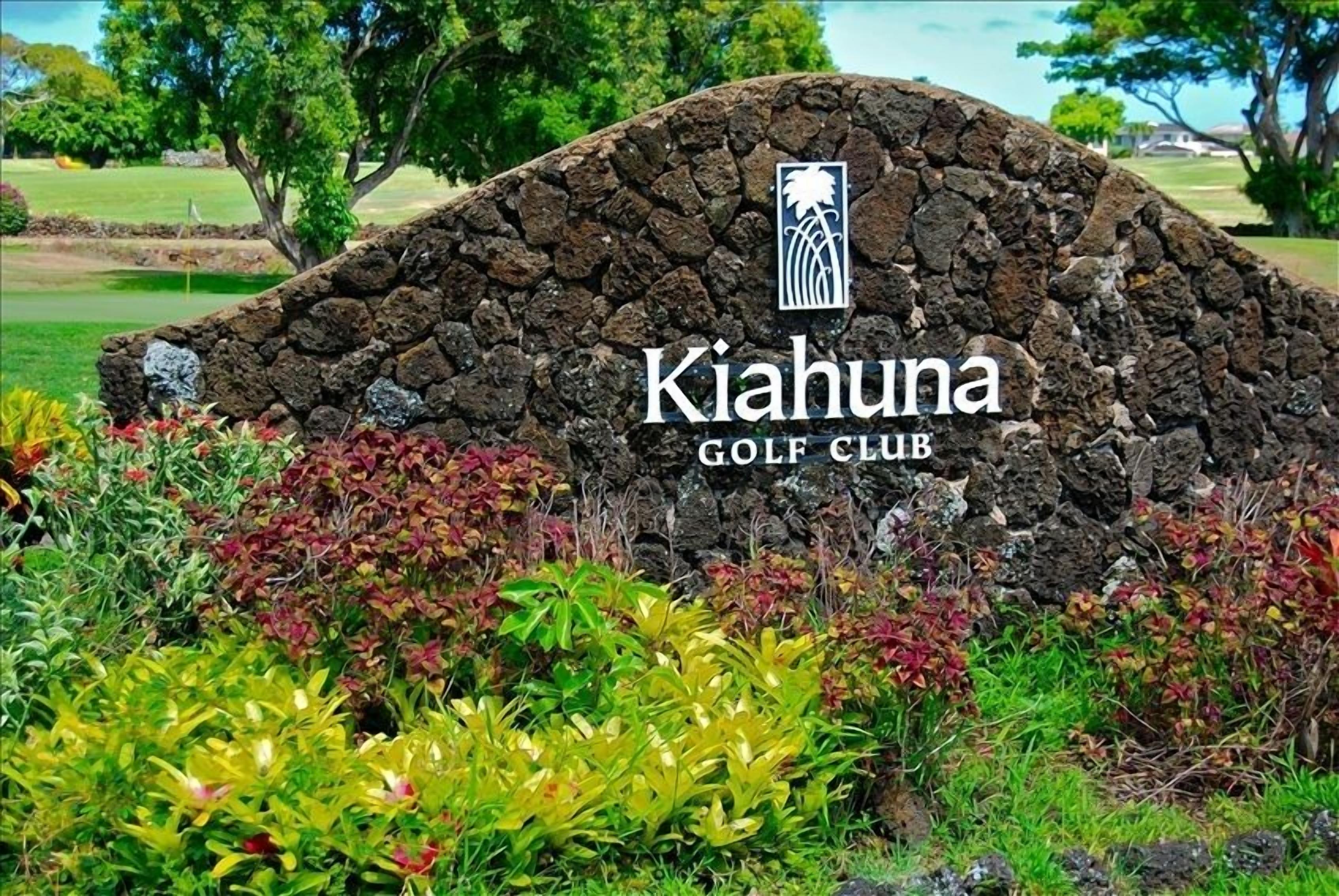 Un mur de pierre sur lequel est inscrit le texte « Kiahuna Golf Club » et un logo.
