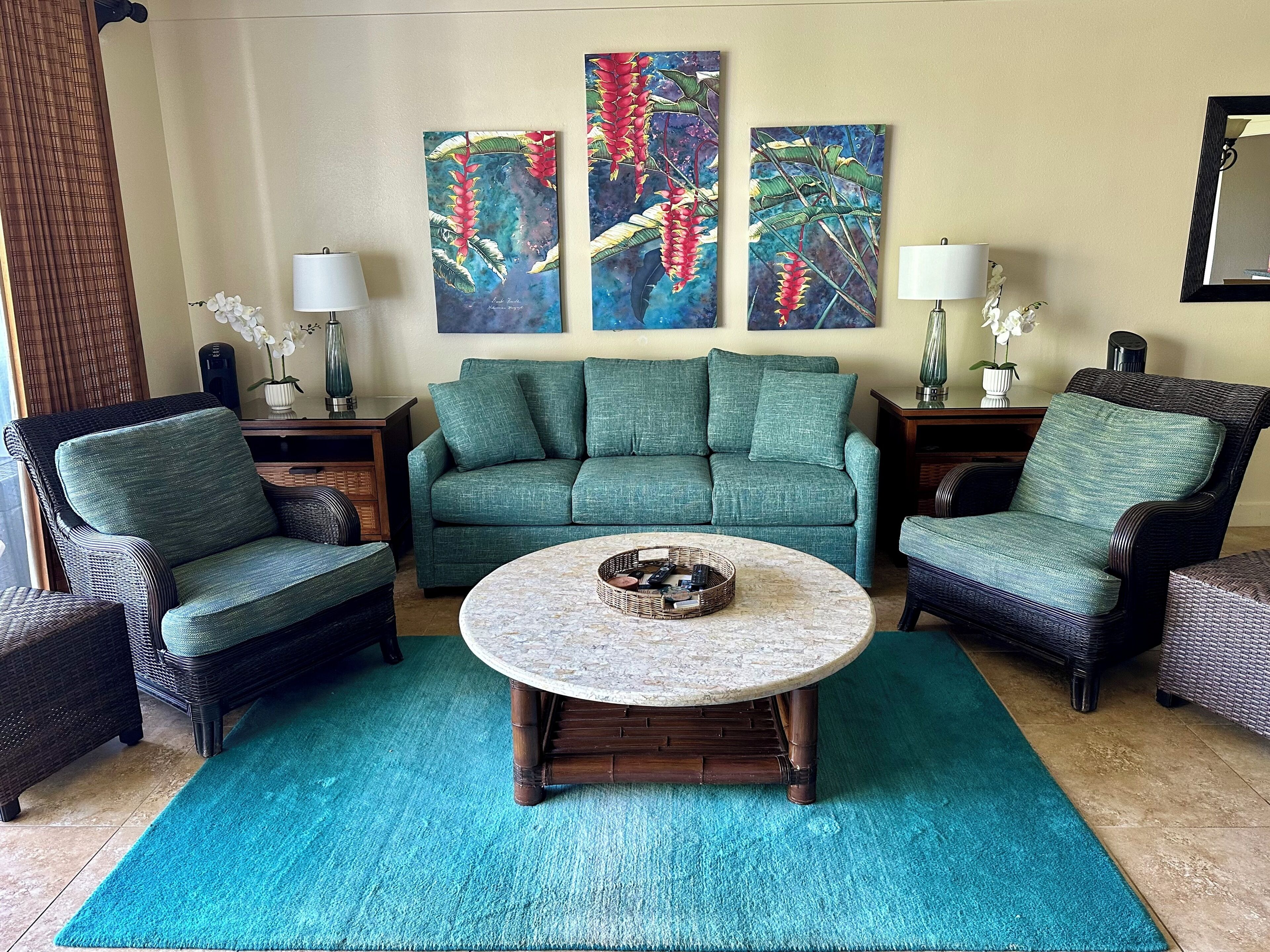 A living room with a green sofa, two armchairs, a coffee table, and three wall-mounted paintings.