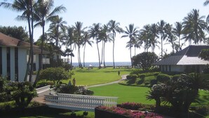 A well-maintained golf course with a clear path, surrounded by lush greenery and palm trees, leading to a view of the ocean. - 2/2 BEACH FRONT RESORT-AC-Poipu Bch, Kiahuna-Garden View, Pool/Gym/Courts (Poipu Beach)