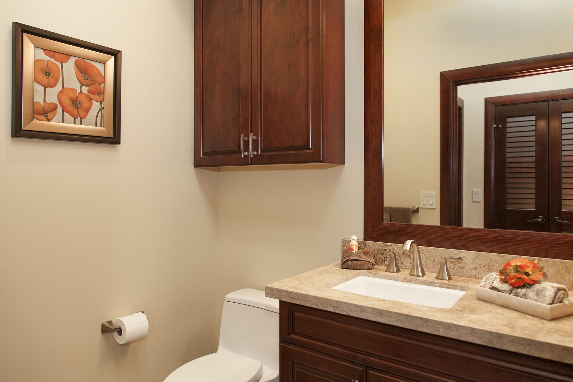 A bathroom with a toilet, sink, and wooden cabinets.