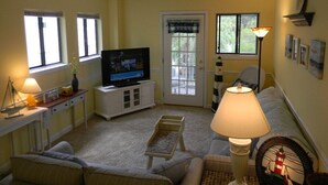 Un salon avec une télévision, une lampe, un canapé et une petite table.