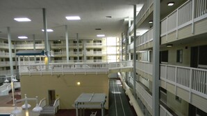 Un atrium intérieur à plusieurs niveaux, doté d’une allée centrale, de rampes blanches et d’un espace piscine avec des chaises longues.