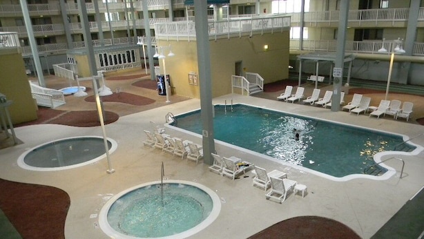 Une piscine intérieure dotée de plusieurs couloirs de nage, de chaises longues et d’un élément décoratif central avec de l’eau.