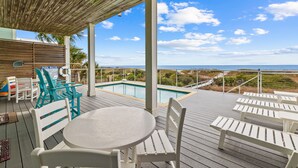 A wooden deck with a pool, white and turquoise chairs, and a table. - Cape Conchs: Large Beachfront Home, Private Pool, Sleeps 18, Pet Friendly (Cape San Blas)