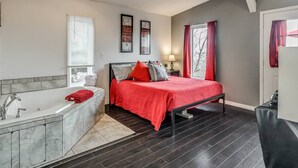 A bedroom with a large bed, a bathtub, and a window with curtains. - Romantic Lakeview Treehouse with Private Jacuzzi (Stigler)