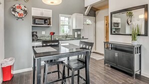 A modern kitchen with a dining area, white cabinets, a black dining table, and a large mirror above the counter. - Romantic Lakeview Treehouse with Private Jacuzzi (Stigler)