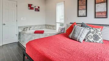 Een slaapkamer met een groot bed, een inloopbad en een raam met zonwering.