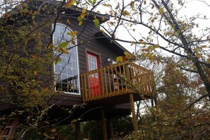 Une maison avec une porte rouge et un balcon en bois.