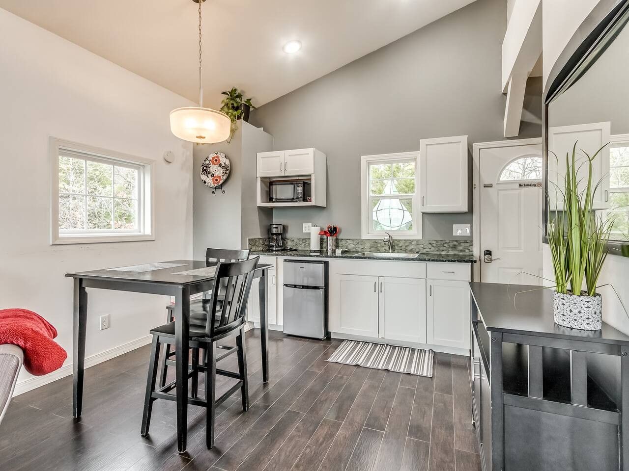 A modern kitchen with a dining area, featuring a refrigerator, microwave, and a dining table with chairs.
