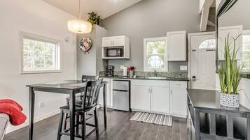 A modern kitchen with a dining area, featuring a refrigerator, microwave, and a dining table with chairs.