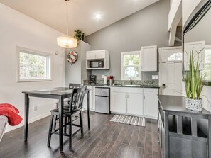 A modern kitchen with a dining area, featuring a refrigerator, microwave, and a dining table with chairs.