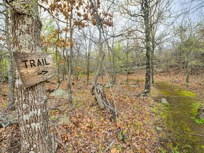 A wooden trail sign in a forested area with a path leading through the woods. - Romantic Lakeview Treehouse with Private Jacuzzi (Stigler)