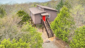 A cabin with a red door, a wooden staircase, and a view of a body of water. - Romantic Lakeview Treehouse with Private Jacuzzi (Stigler)