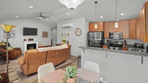 A modern living room with a sofa, a dining table, and a kitchen area with appliances. - Stylish Two-Story Getaway on Keizer's Quiet Outskirts (Keizer)