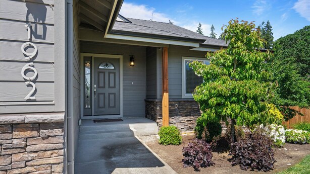 A house with a stone facade, a front door, and a well-maintained garden with various plants. - Stylish Two-Story Getaway on Keizer's Quiet Outskirts (Keizer)