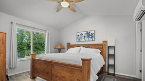 A bedroom with a wooden bed, a ceiling fan, a window with blinds, a bedside table with a lamp, and a wall-mounted shelf. - Stylish Two-Story Getaway on Keizer's Quiet Outskirts (Keizer)