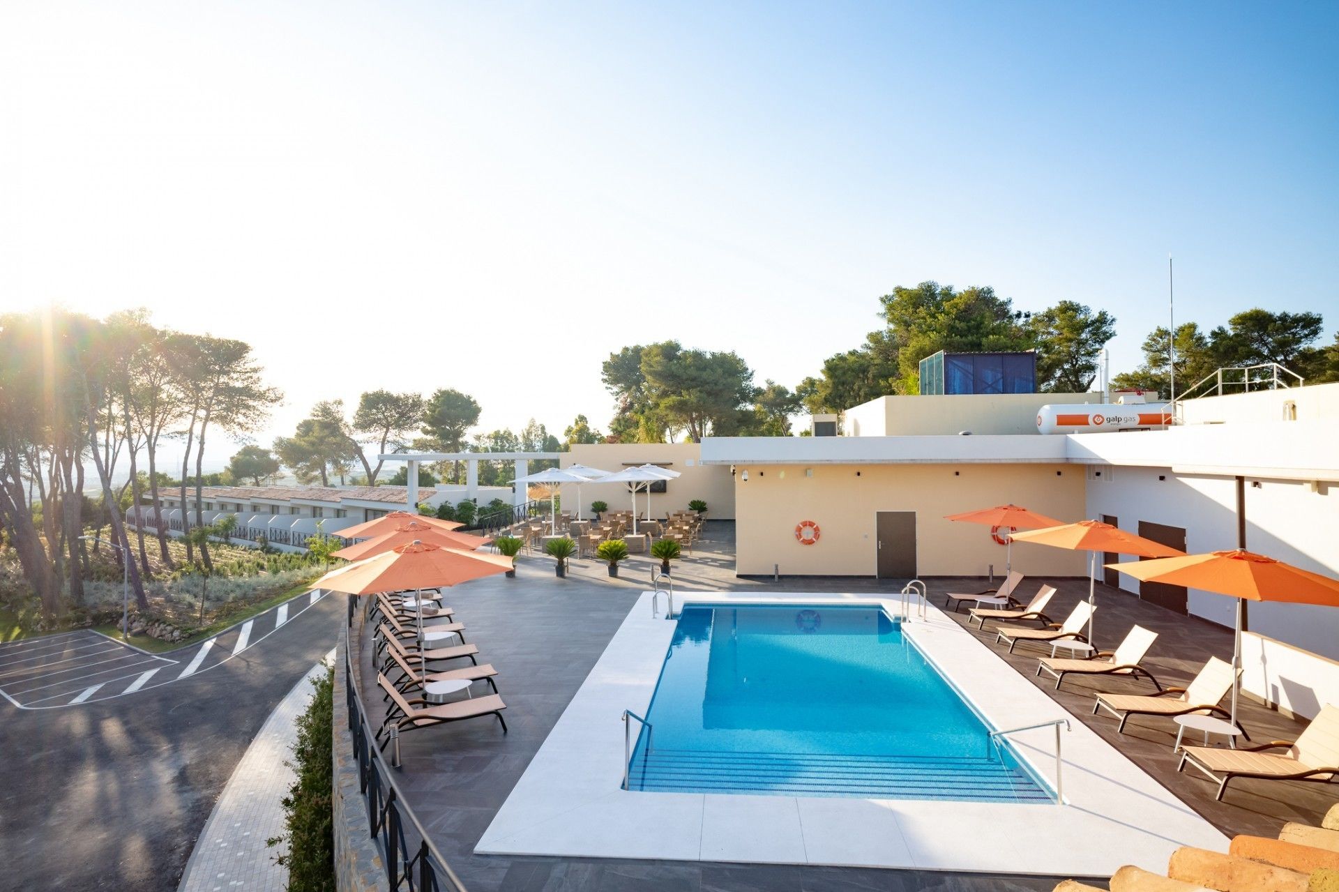 Een buitenzwembad, parasols bij het zwembad en ligstoelen