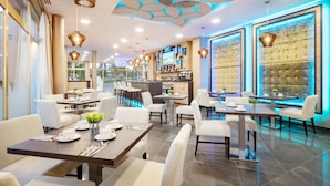 Een modern restaurant met een bar, witte meubels en een bijzonder plafondontwerp.