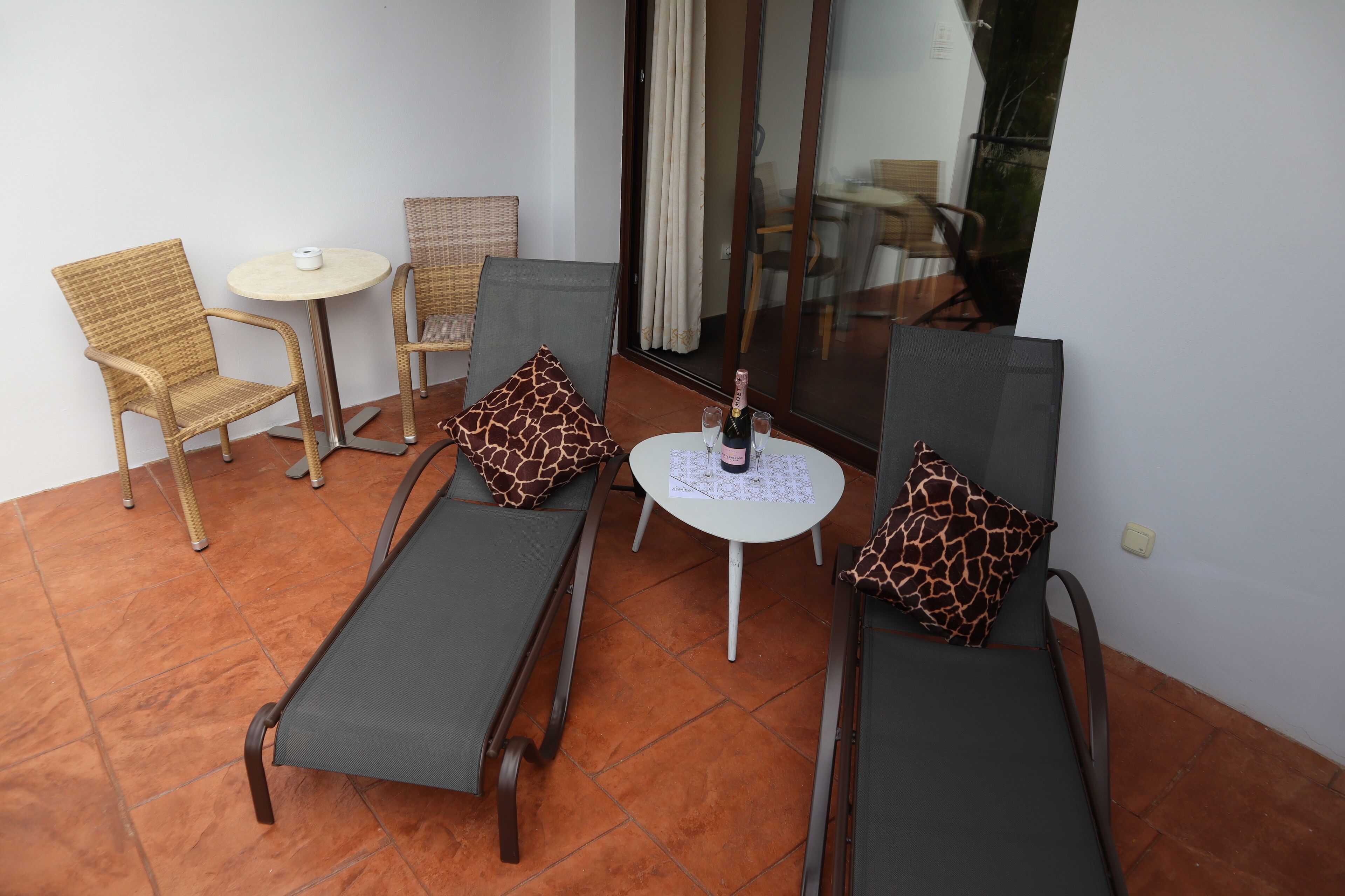 Una terraza con dos sillones de descanso, una mesita redonda y una botella de champán.