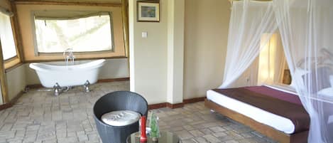 A bathroom with a bathtub, a bed with a canopy, wicker furniture, and a small table with decorative items.
