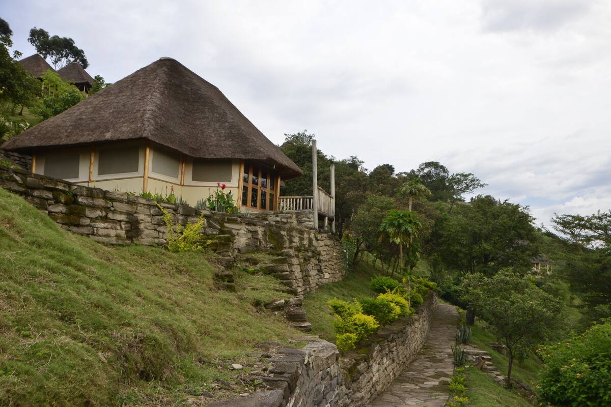 A thatched-roof house with a stone retaining wall and a stone pathway.