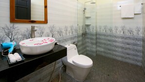 A modern bathroom with a glass shower enclosure, a white sink with a marble countertop, and a toilet. - Home Sweet Home Villa (Da Nang)