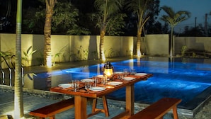 An outdoor dining area with a pool, wooden benches, and a table set for a meal. - Home Sweet Home Villa (Da Nang)