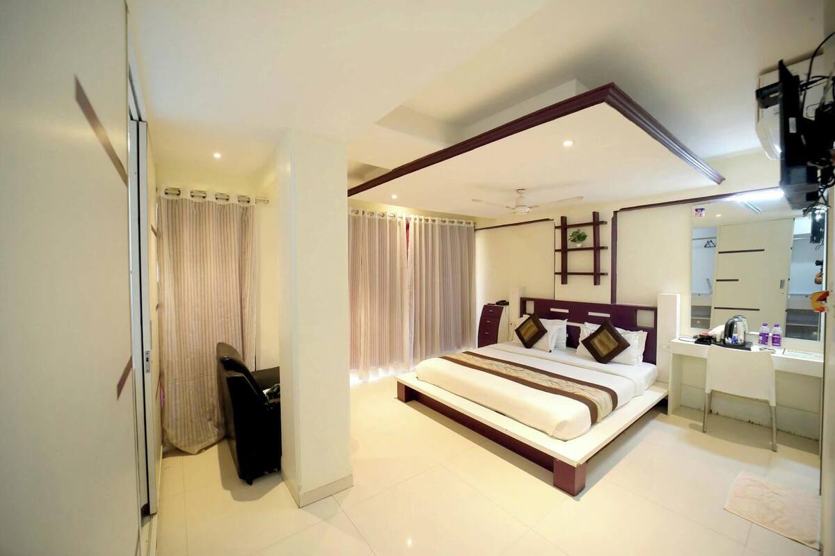 A modern hotel room with a large bed, a desk, and a mirror.