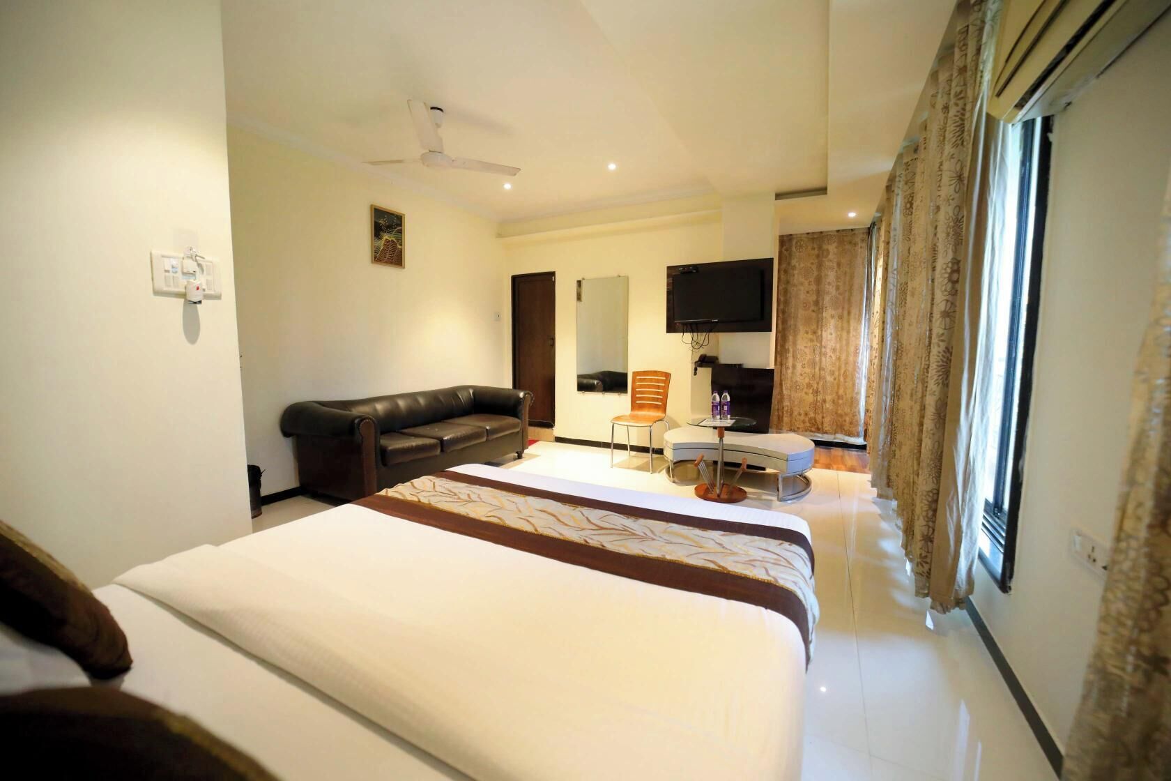 Habitación de hotel con una cama grande, un sofá, un televisor y una mesita con botellas.
