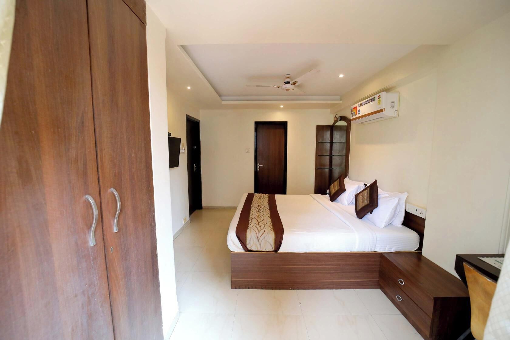 Un dormitorio con una cama grande, armario de madera y ventilador de techo.