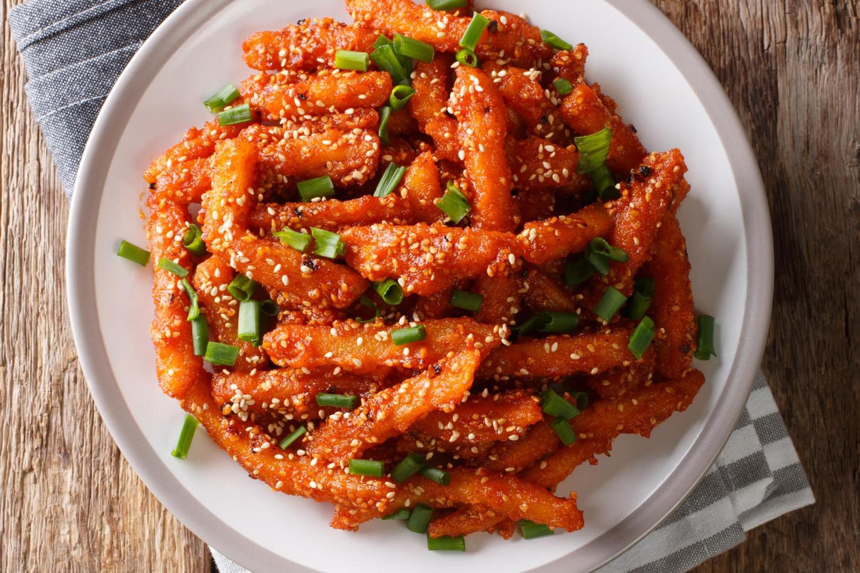 A plate of Korean chicken wings garnished with sesame seeds and chopped green onions.
