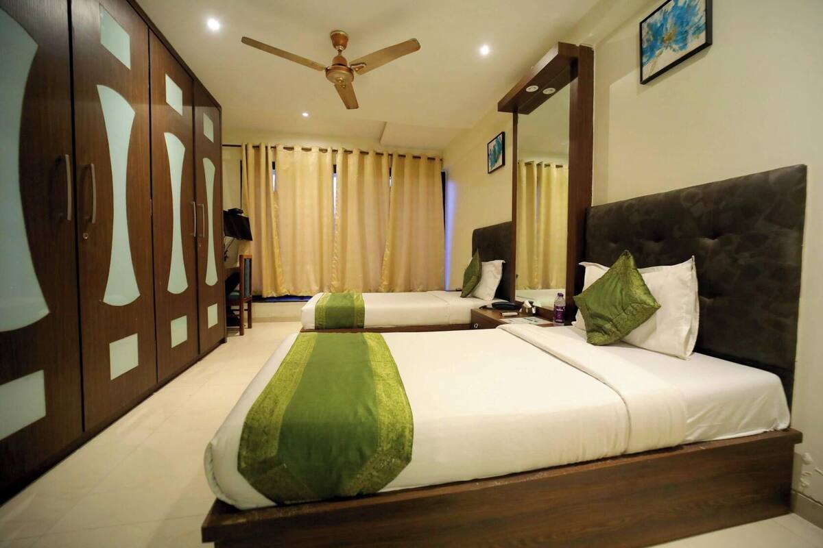 A hotel room with two beds, a ceiling fan, and a large wardrobe.