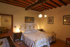 A bedroom with a double bed, two bedside tables, a wooden bench, and a chair.